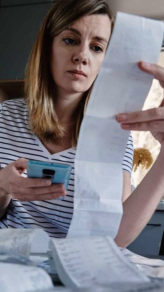 A person reviewing an electricity bill  as part of money mistakes to avoid when living alone