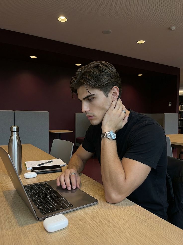 a young guy sitting while focused on his laptop