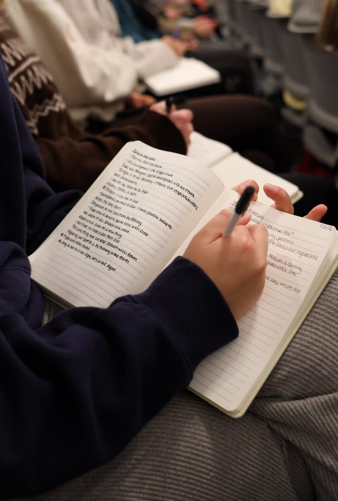 A person writing notes in a journal about what they learned during their first week in a new apartment