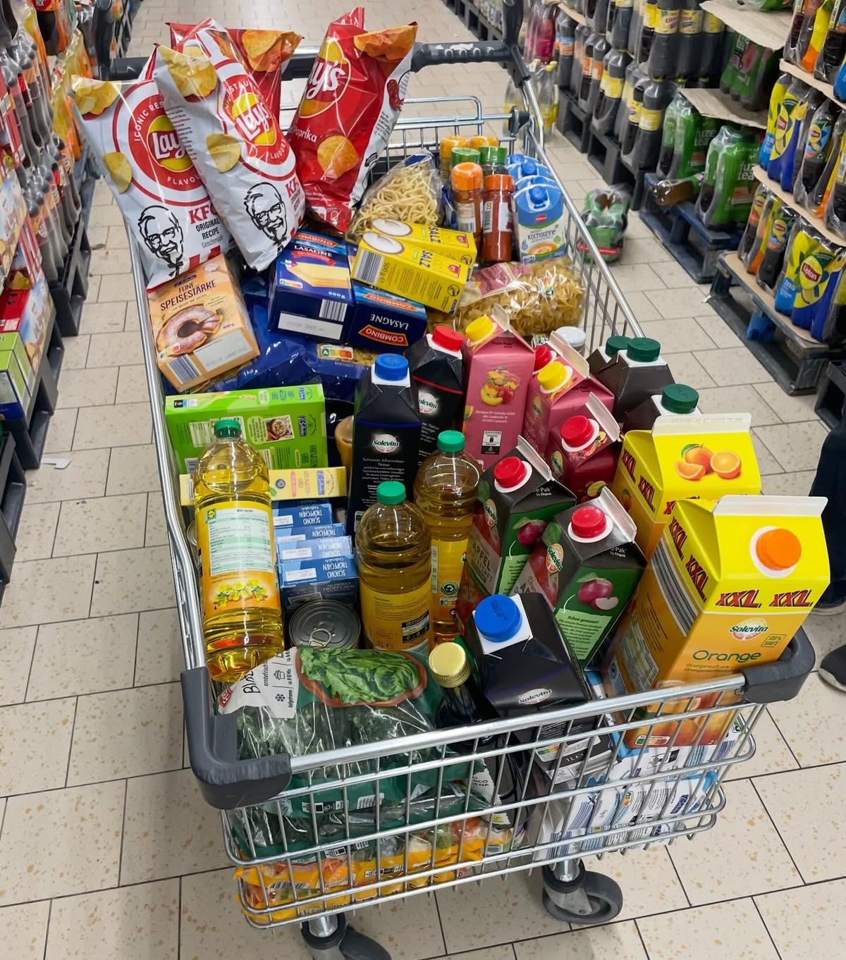 A very full shopping cart with more groceries than one person needs.
