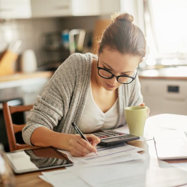 A young adult sitting at a small table with receipts  as regards to first week living alone