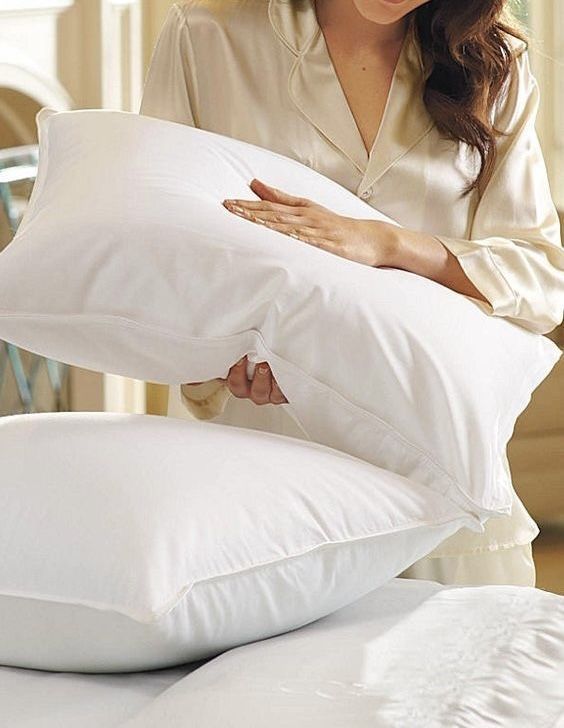 Young adult arranging a comfortable pillows on a simple bed as one of first apartment essentials