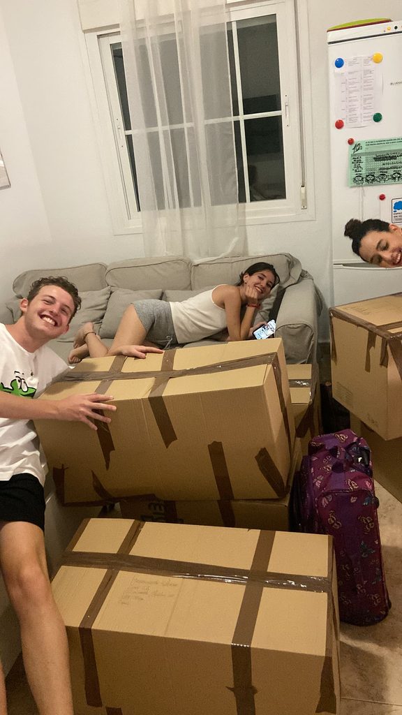 A few friends visiting a simple new apartment while some moving boxes are still visible in the background.