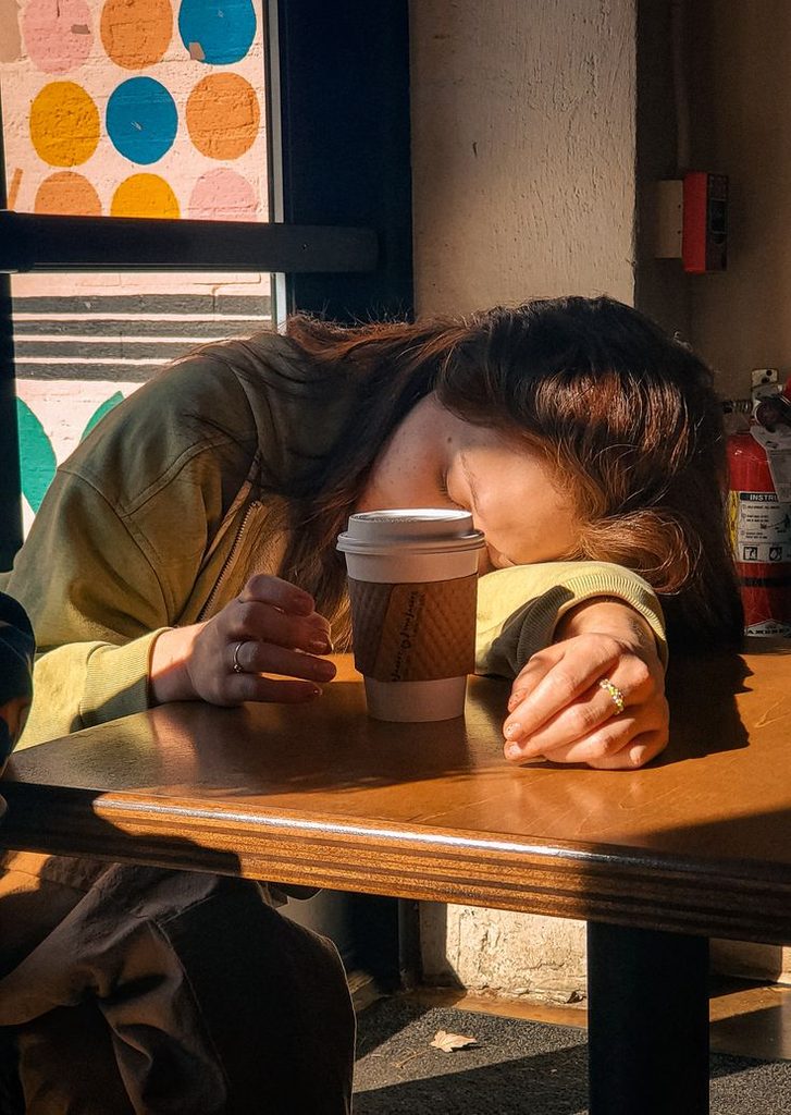 lady resting on a desk with a can of drink behind