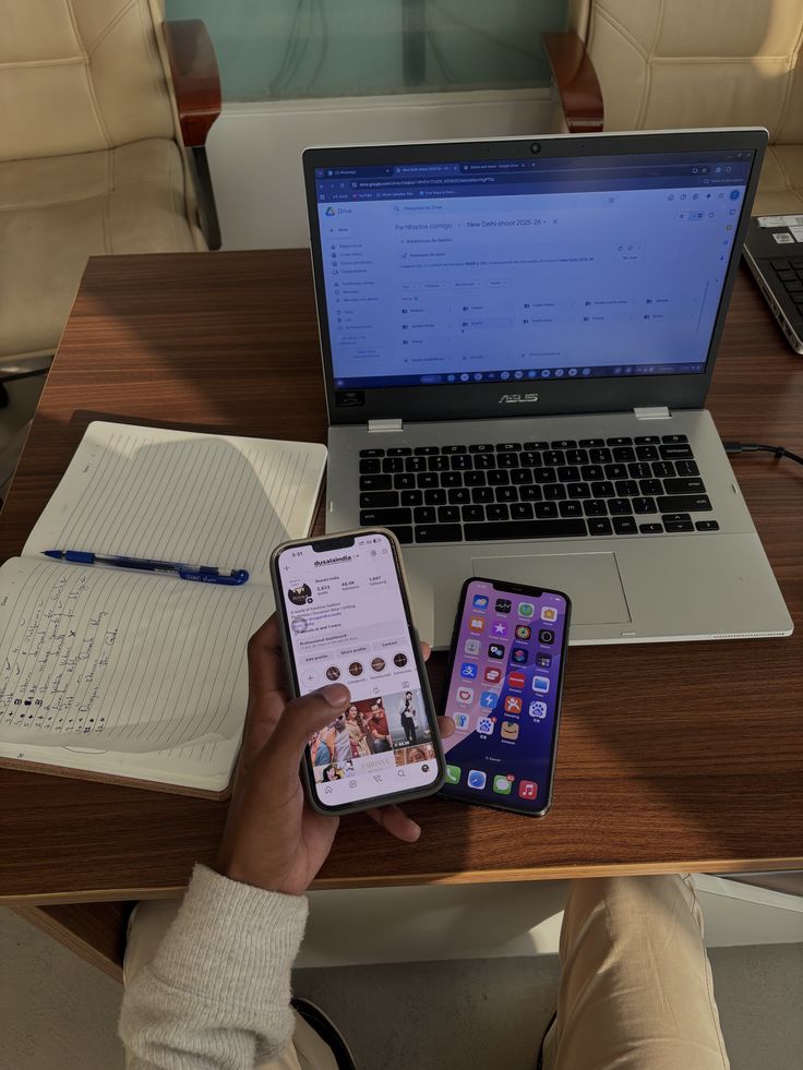 young adult sitting with two phones and laptop